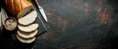 Pieces of bread with a knife, grain and spikelets. photo