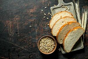 Pieces of bread on a cutting Board with grains and spikelets. photo