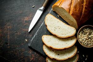 rebanado Fresco un pan con el cuchillo y el grano en el bol. foto