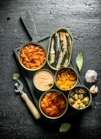 Open tin cans of canned food on the cutting Board. photo