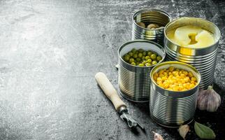 Canned pineapples, green peas, corn and mushrooms in open cans. photo