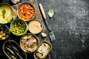 Canned food in various open tin cans on the cutting Board. photo