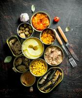 Open tin cans of canned mushrooms, pineapples, corn, meat and fish. photo