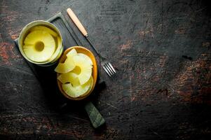 Canned pineapples in a tin can and on a plate. photo