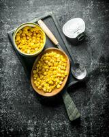 Open tin can with canned corn on the cutting Board. photo