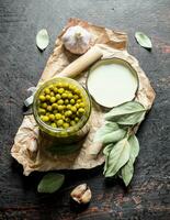 Open jar with canned green peas on paper. photo