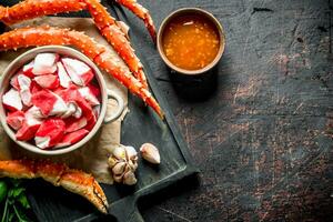 Crab meat in bowl and fresh crab with sauce and garlic cloves. photo