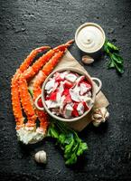 Crab meat in bowl on paper with greens, sauce and garlic. photo