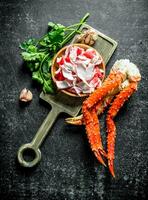 Crab meat and fresh crab on a cutting Board with greens and garlic. photo