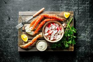 Crab meat and fresh crab on a wooden tray with lemon slices, sauce and herbs. photo