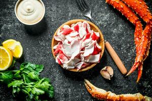 Crab meat on a plate with sauce, lemon and parsley. photo