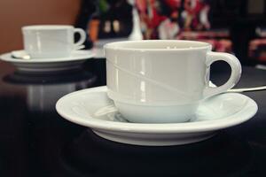 llanura pequeño blanco taza con caliente bebida en café foto
