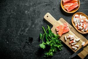 Chopped crab sticks with a knife and parsley. photo