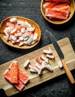 Sliced crab sticks on a cutting Board with a knife. photo