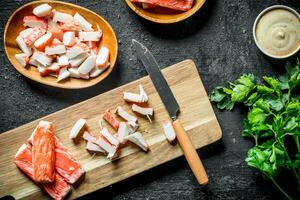 Sliced crab sticks on a cutting Board with a knife. photo