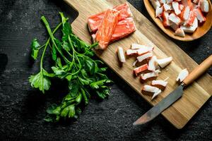 Chopped crab sticks with a knife and parsley. photo