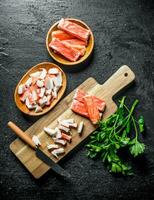 Chopped crab sticks with a knife and parsley. photo