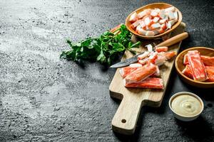 Sliced crab sticks with sauce and parsley. photo