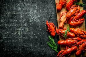 Boiled crayfish on a wooden cutting Board with dill. photo