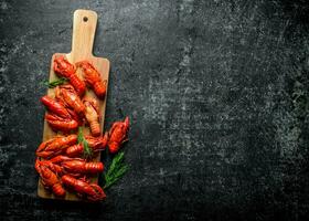 Boiled crayfish on a wooden cutting Board with dill. photo