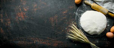 Dough with eggs, rolling pin and spikelets. photo