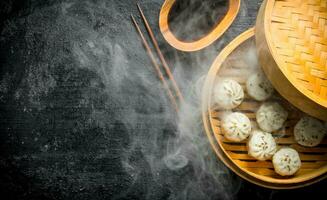 Hot dumplings manta in a bamboo steamer with soy sauce. photo