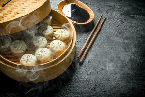 Hot dumplings manta in a bamboo steamer with soy sauce. photo