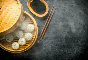 Hot dumplings manta in a bamboo steamer with soy sauce. photo