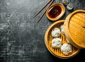 Fragrant manta dumplings in a bamboo steamer with soy sauce. photo