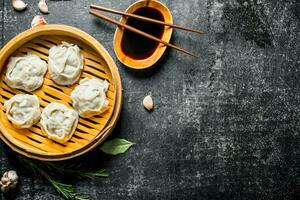 Traditional food. Manta dumplings in bamboo steamer with soy sauce. photo