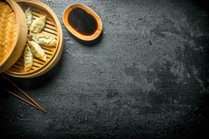 Hot Chinese traditional gedza dumplings in bamboo steamer with soy sauce. photo