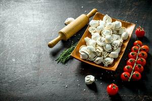 Raw dumpling with tomatoes and rosemary. photo