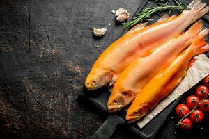 Raw trout on a cutting Board with tomatoes, rosemary and garlic cloves. photo