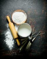 Flour with spikelets, rolling pin and milk in a jug. photo