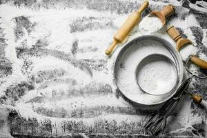 Flour with a sieve, scoops, rolling pin and mixer. photo