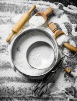 Flour with a sieve, scoops, rolling pin and mixer. photo