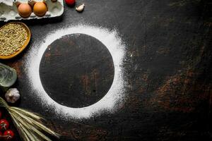 Round frame made of flour with spikelets, grain and eggs. photo