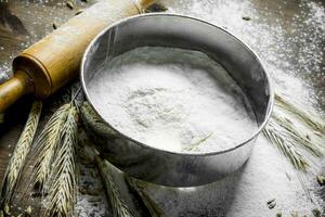 Texture wheat flour with a sieve and rolling pin. photo