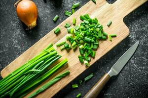 Chopped green onion on a cutting Board with a knife and onion. photo