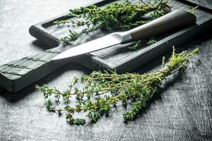 Thyme with a cutting Board and a knife. photo