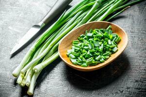 Chopped green onion in a wooden plate. photo