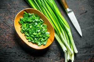 Chopped green onion in a wooden plate. photo