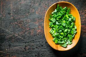 Chopped green onion in a wooden plate. photo