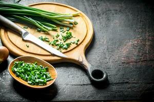 Chopped green onion on a cutting Board with a knife. photo