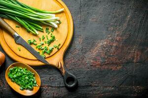 Chopped green onion on a cutting Board with a knife. photo