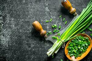 Chopped green onion in a wooden plate with a knife. photo