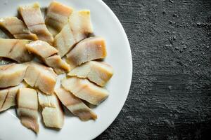 Pieces of salted herring on a plate. photo