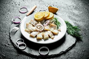 Fillet of salted herring with slices of lemon, onion and herbs. photo