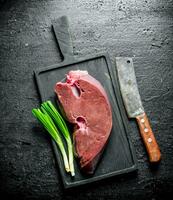 Raw liver on a cutting Board with green onions. photo