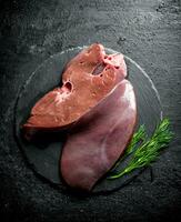 Raw liver with dill on a stone Board. photo